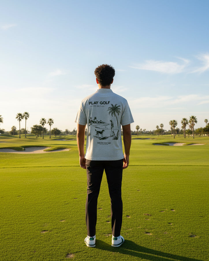 Person standing on a golf course wearing a 'Play Golf' t-shirt with palm tree design.