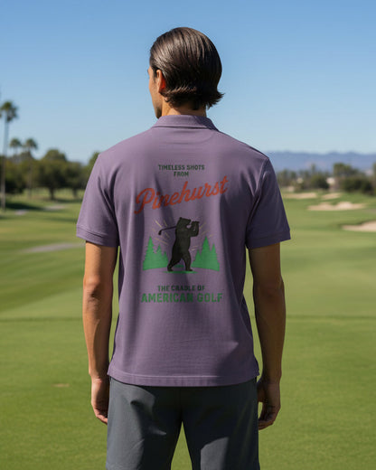 Person wearing a purple golf shirt with branding on a golf course
