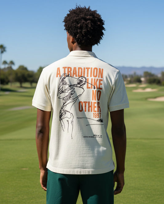 Person wearing a white polo shirt with text and graphics on the back, standing on a golf course.